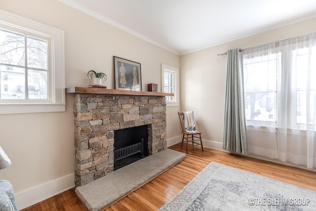 living area with crown molding, a fireplace, baseboards, and wood finished floors