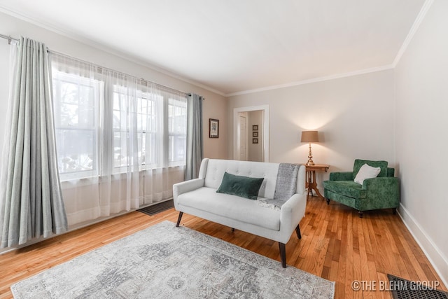 sitting room with baseboards, wood finished floors, visible vents, and crown molding