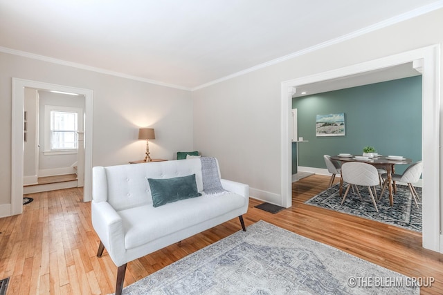 living room featuring wood finished floors, visible vents, baseboards, stairway, and crown molding