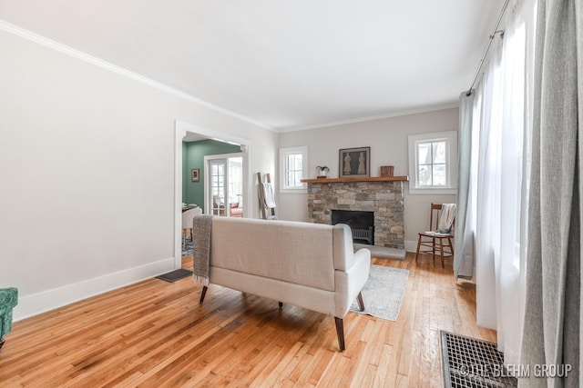 living room featuring a fireplace, crown molding, visible vents, light wood-style floors, and baseboards