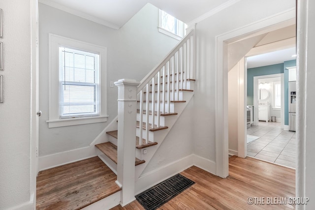 stairs with baseboards, wood finished floors, visible vents, and crown molding