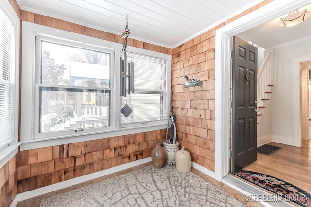 interior space with ornamental molding, visible vents, wood walls, and baseboards