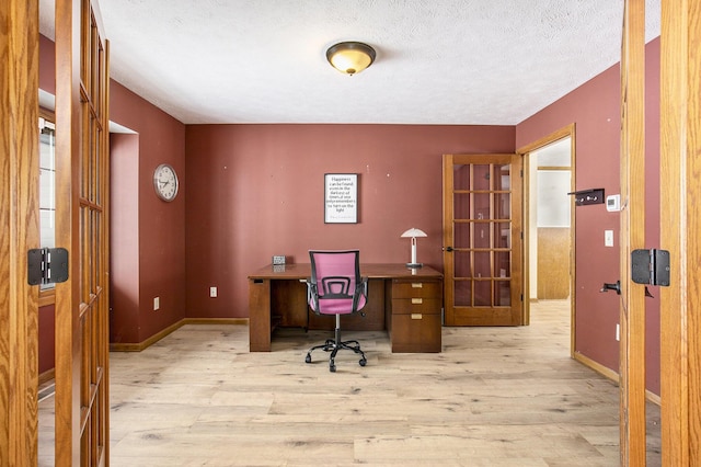 office featuring a textured ceiling, light wood finished floors, and baseboards