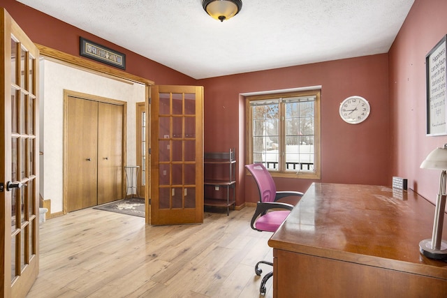 office area with light wood finished floors, baseboards, a textured ceiling, and french doors