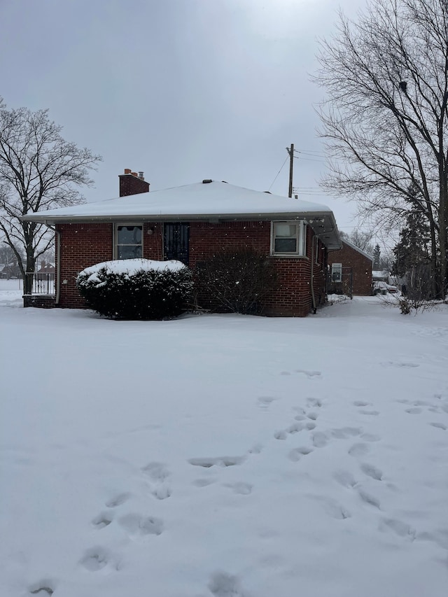 view of front of home featuring a chimney and brick siding