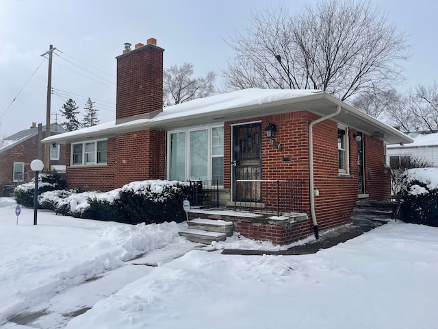 view of front of house featuring brick siding and a chimney