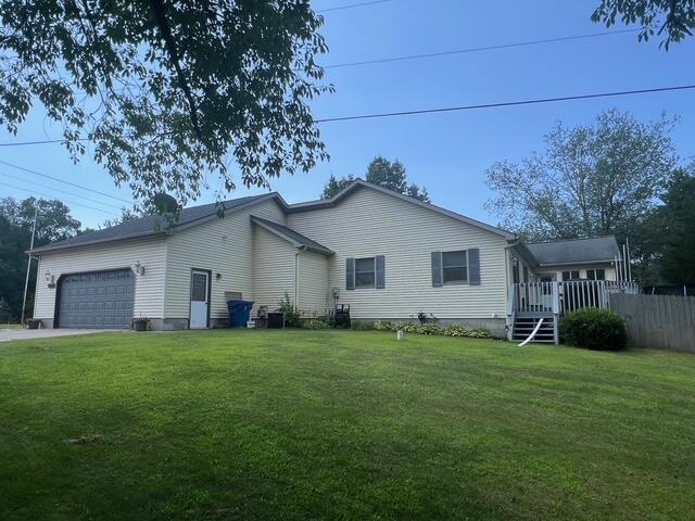 rear view of house with a yard, an attached garage, fence, and driveway