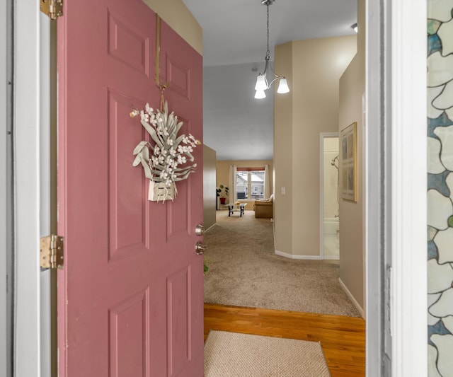 carpeted foyer entrance featuring wood finished floors and baseboards