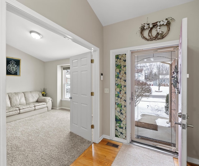 entryway featuring carpet floors, wood finished floors, visible vents, and baseboards