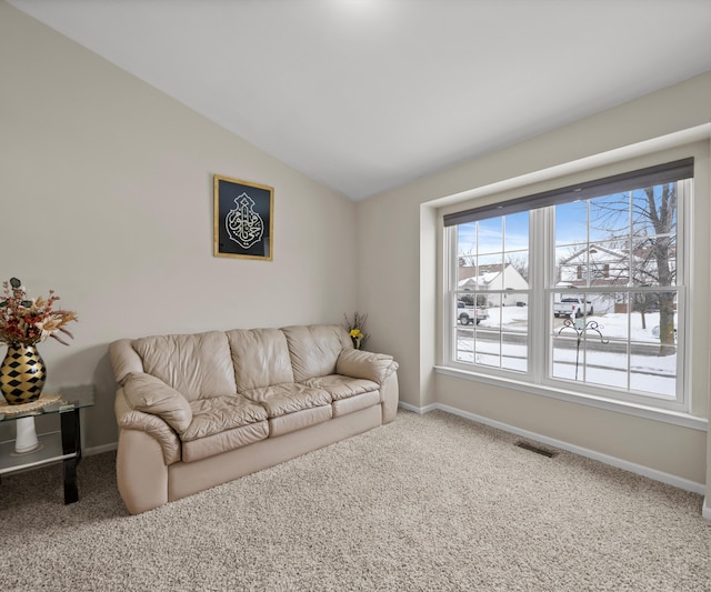 carpeted living room featuring lofted ceiling, visible vents, and baseboards