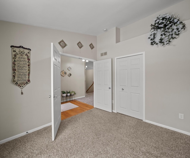 carpeted empty room featuring lofted ceiling, baseboards, and visible vents