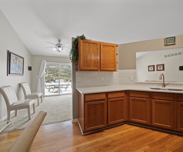 kitchen featuring brown cabinetry, visible vents, light countertops, and a sink