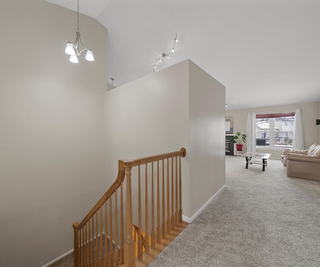 hallway with a chandelier, carpet flooring, an upstairs landing, baseboards, and vaulted ceiling