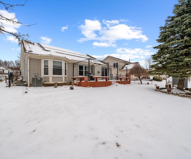 snow covered back of property with a deck