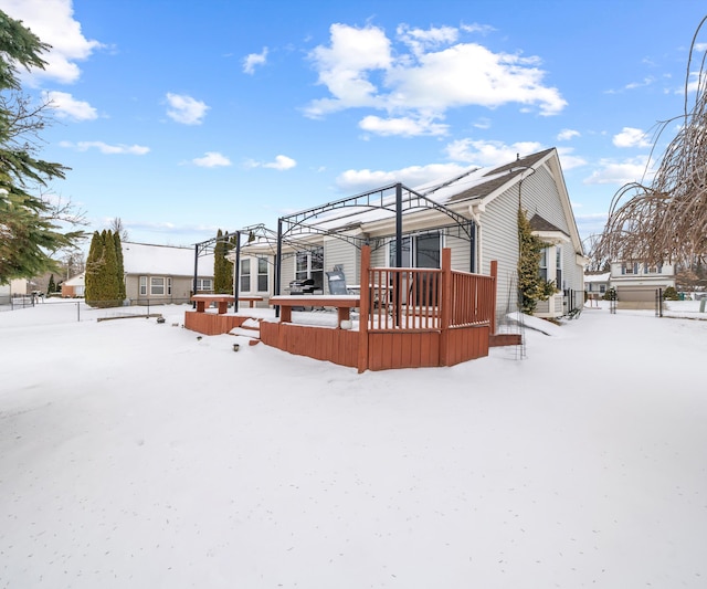 snow covered back of property with a wooden deck