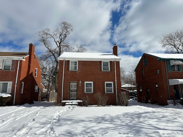 snow covered back of property with brick siding and a chimney