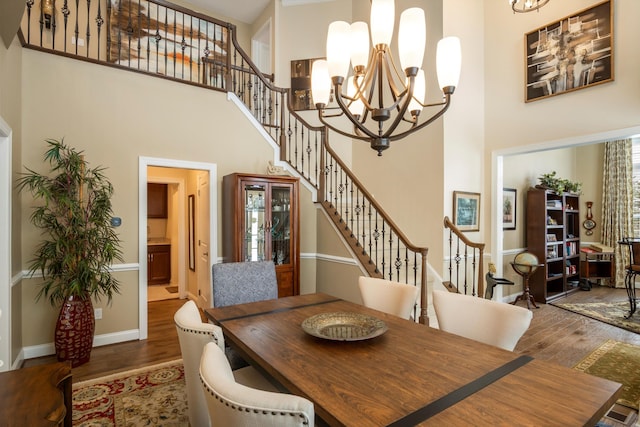 dining room featuring a high ceiling, stairs, a chandelier, and wood finished floors