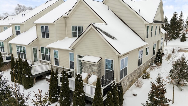 snow covered house with cooling unit and a wooden deck