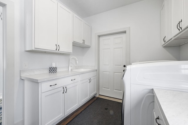 clothes washing area with washer / clothes dryer, a sink, and cabinet space