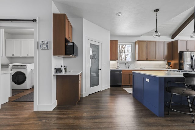 kitchen featuring appliances with stainless steel finishes, brown cabinets, hanging light fixtures, light countertops, and separate washer and dryer