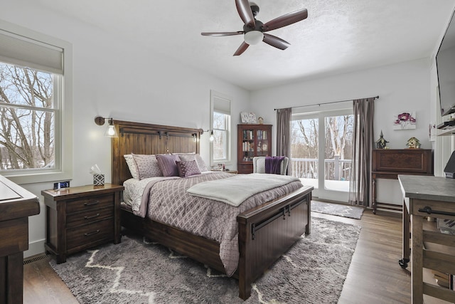 bedroom with a textured ceiling, access to outside, wood finished floors, and a ceiling fan