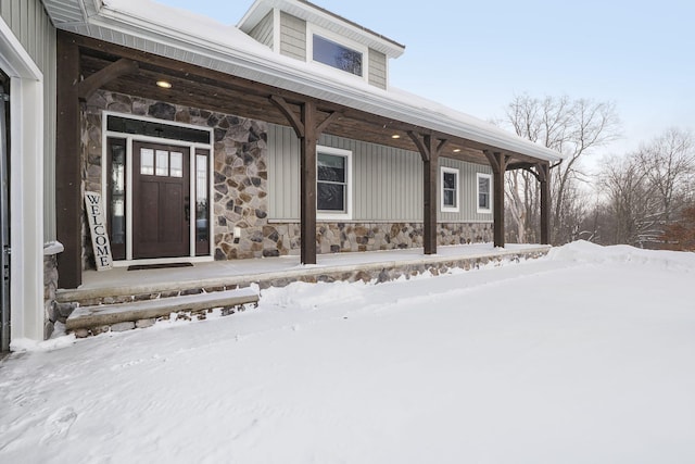 snow covered property entrance with stone siding