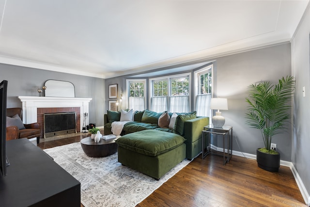 living area with crown molding, dark wood-style flooring, a fireplace, and baseboards