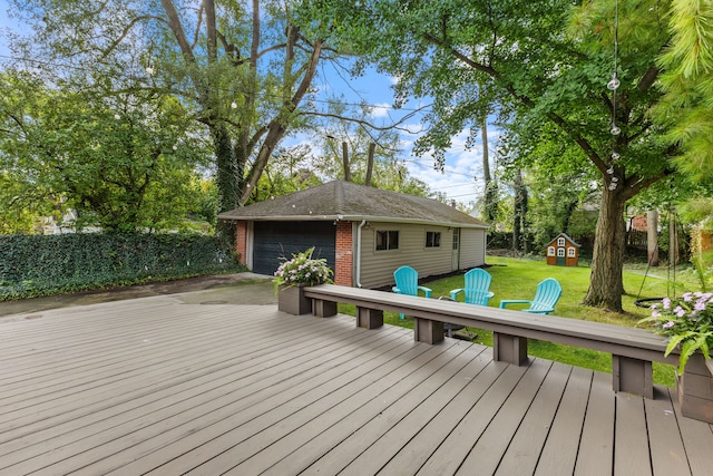 wooden deck featuring a fire pit, a detached garage, an outbuilding, a yard, and a playground