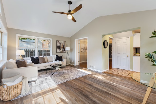 living area featuring visible vents, light wood-style floors, a ceiling fan, vaulted ceiling, and baseboards