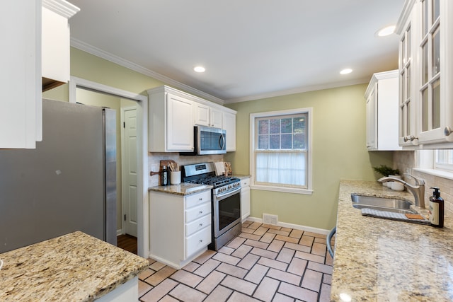 kitchen with stainless steel appliances, a sink, visible vents, white cabinetry, and decorative backsplash