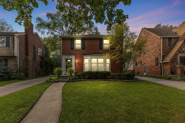 view of front facade with a lawn and brick siding