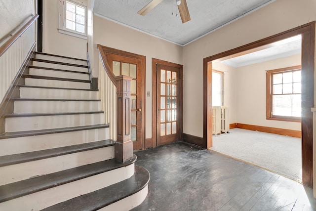 foyer entrance with dark wood-style floors, crown molding, stairway, radiator heating unit, and baseboards