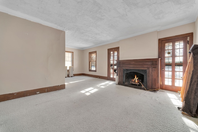 unfurnished living room with french doors, radiator heating unit, a fireplace with flush hearth, a textured ceiling, and baseboards