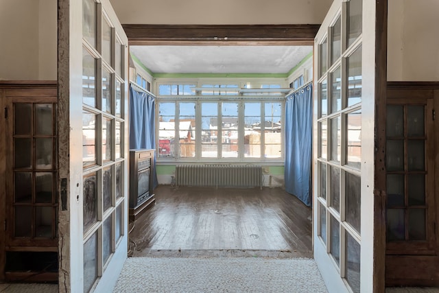 unfurnished sunroom featuring radiator heating unit and french doors