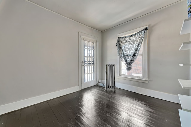 unfurnished room with radiator, dark wood-type flooring, and baseboards