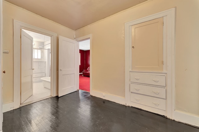 unfurnished bedroom with connected bathroom and dark wood-type flooring