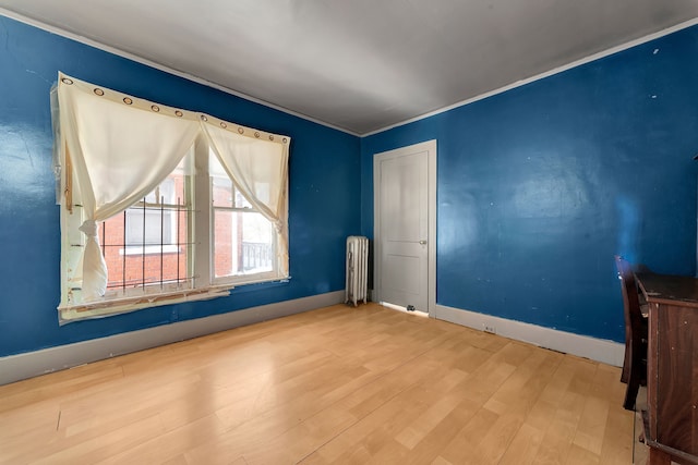 empty room with radiator, baseboards, and wood finished floors