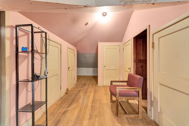 corridor with light wood-type flooring and vaulted ceiling