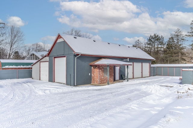 snow covered back of property with a garage and brick siding