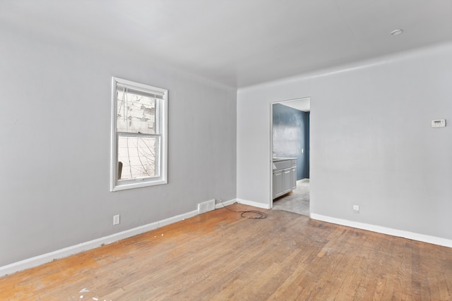 unfurnished room featuring baseboards, visible vents, and light wood-style floors