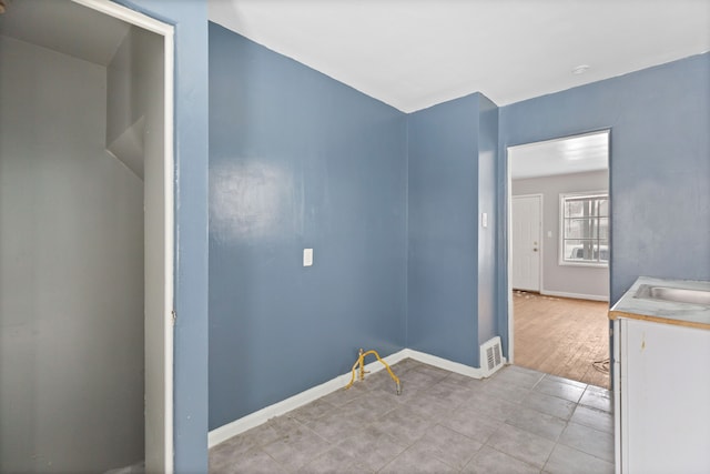 empty room featuring baseboards, visible vents, and a sink