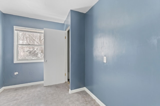 empty room with light tile patterned flooring and baseboards