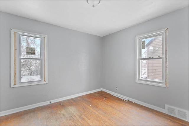 empty room featuring light wood finished floors, visible vents, and baseboards