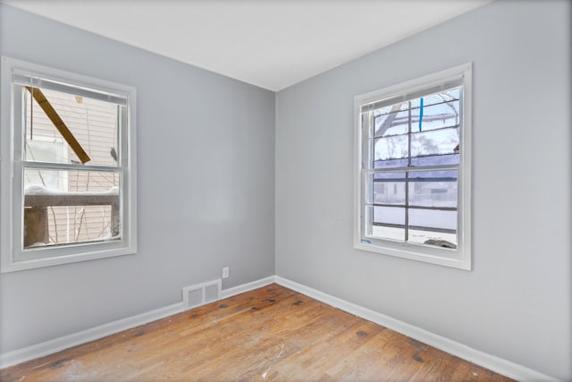 empty room featuring visible vents, baseboards, and wood finished floors