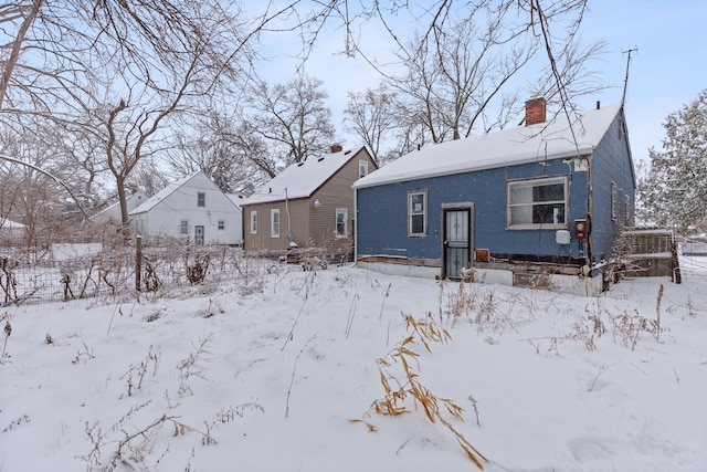 snow covered property with a chimney