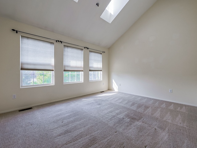 carpeted spare room featuring high vaulted ceiling, a wealth of natural light, visible vents, and a skylight