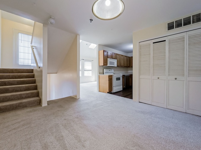 kitchen featuring white appliances, visible vents, brown cabinets, light countertops, and dark carpet