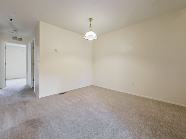 empty room with baseboards, visible vents, and light colored carpet