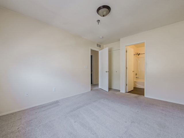 unfurnished bedroom featuring ensuite bath, visible vents, baseboards, and light colored carpet