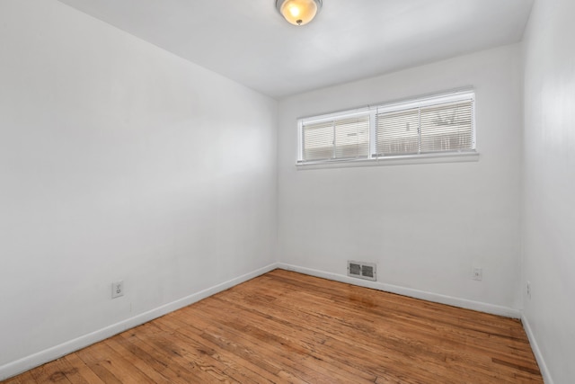 spare room featuring wood finished floors, visible vents, and baseboards